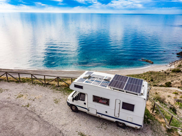 A motorhome equipped with solar panels is traveling by the lake