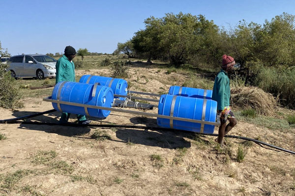 Two people carrying four buckets of irrigation system